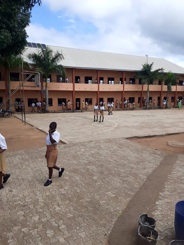 A Kusaki student in uniform crossing the courtyard in front of the main classroom block